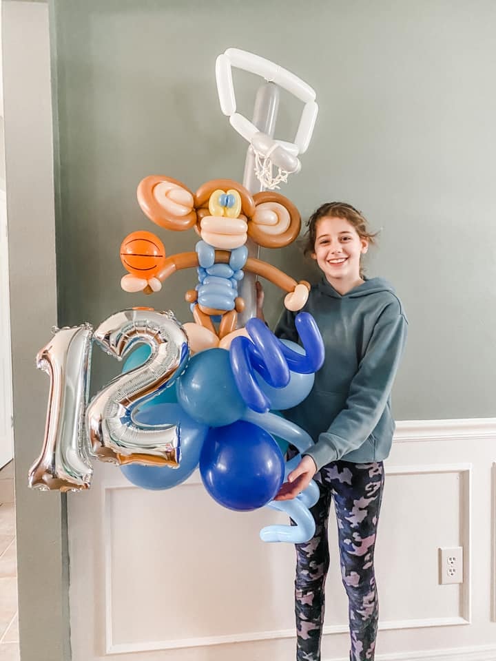 Girl with monkey basketball hoop balloon sculpture for 12th birthday