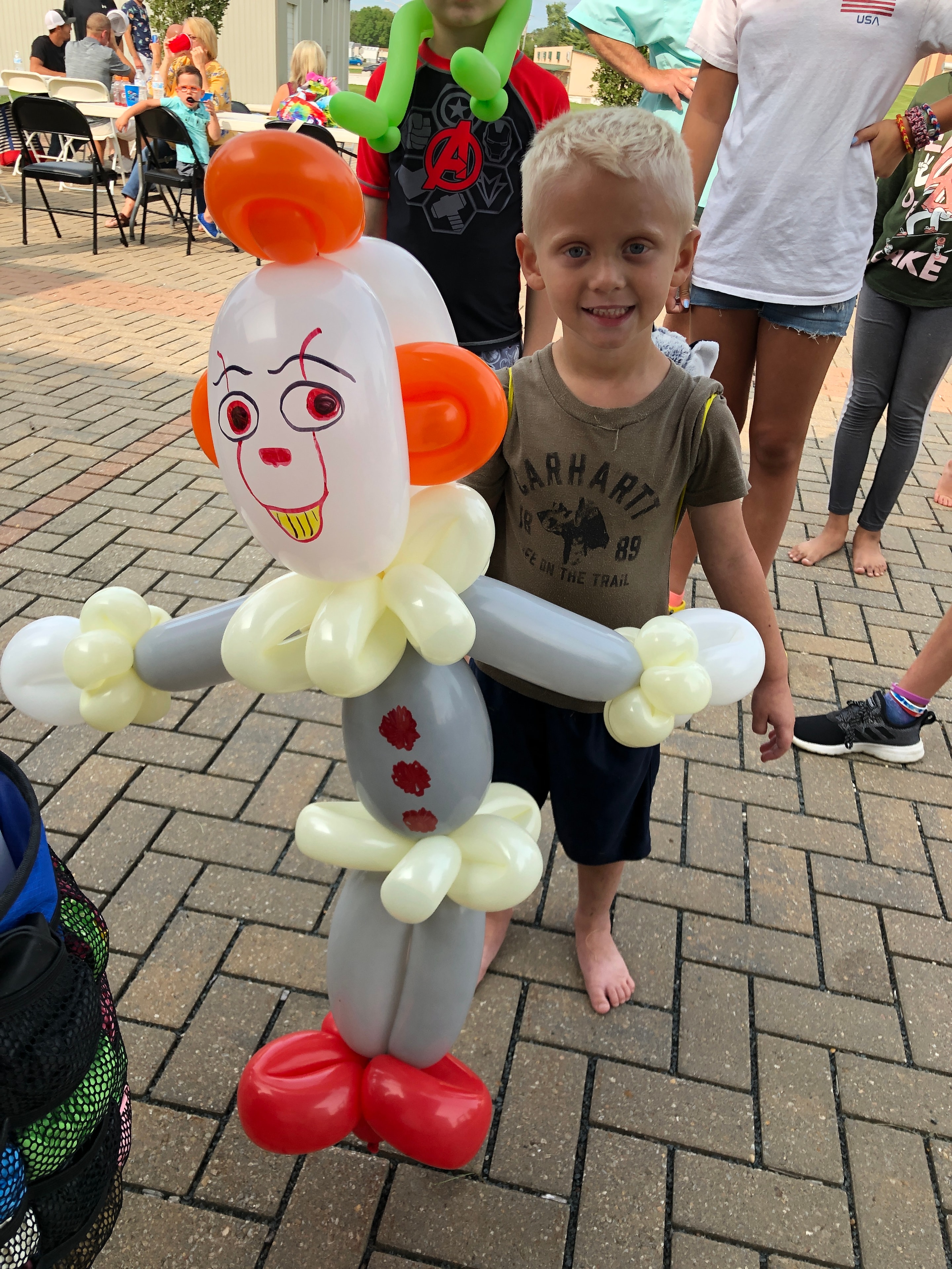 Kids with Pennywise character balloon at outdoor event